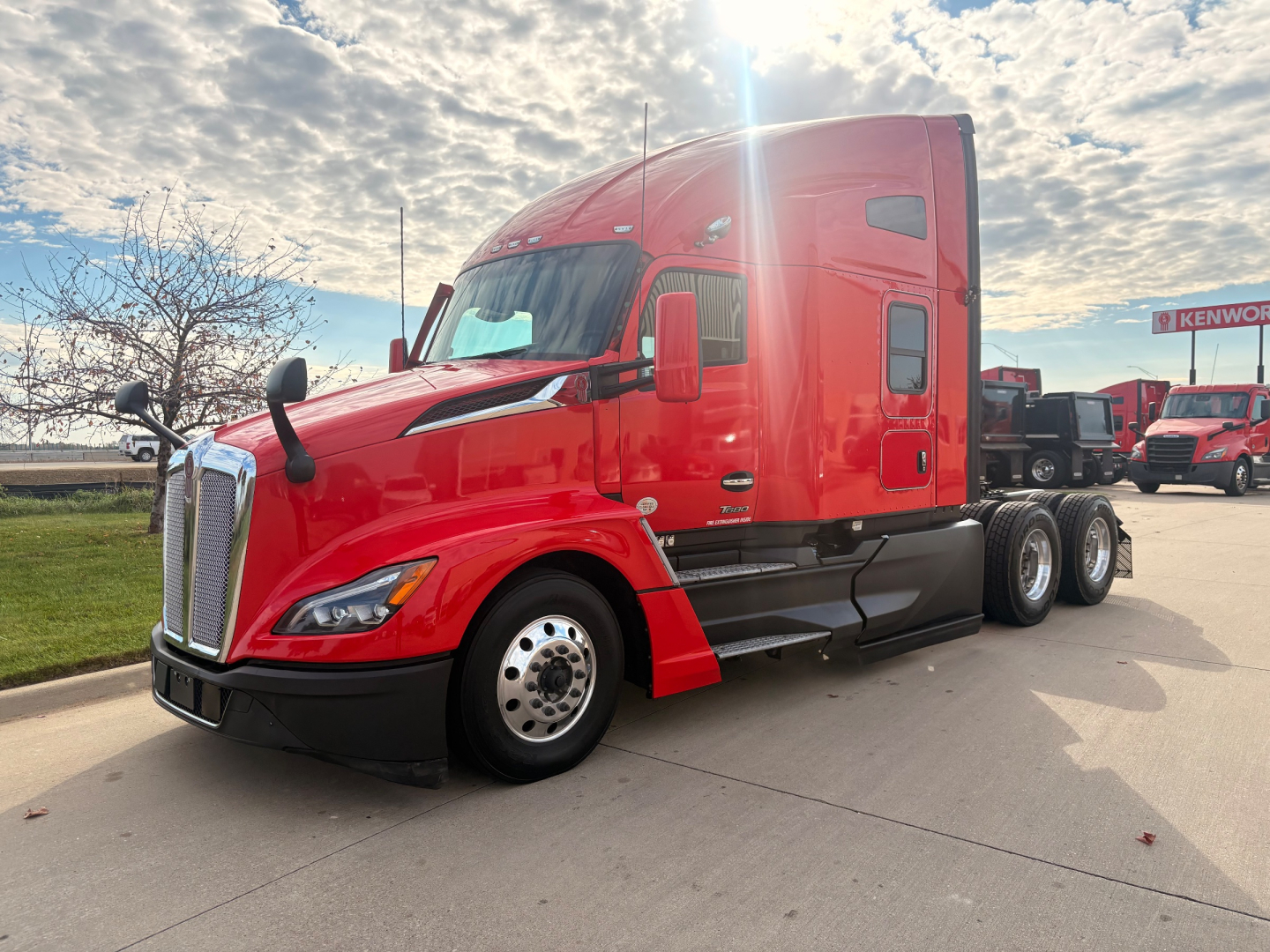 Kenworth T680 tractor-trailer in red, side view showing aerodynamic hood, sleeper cab, dual rear axles, chrome grille and wheels.
