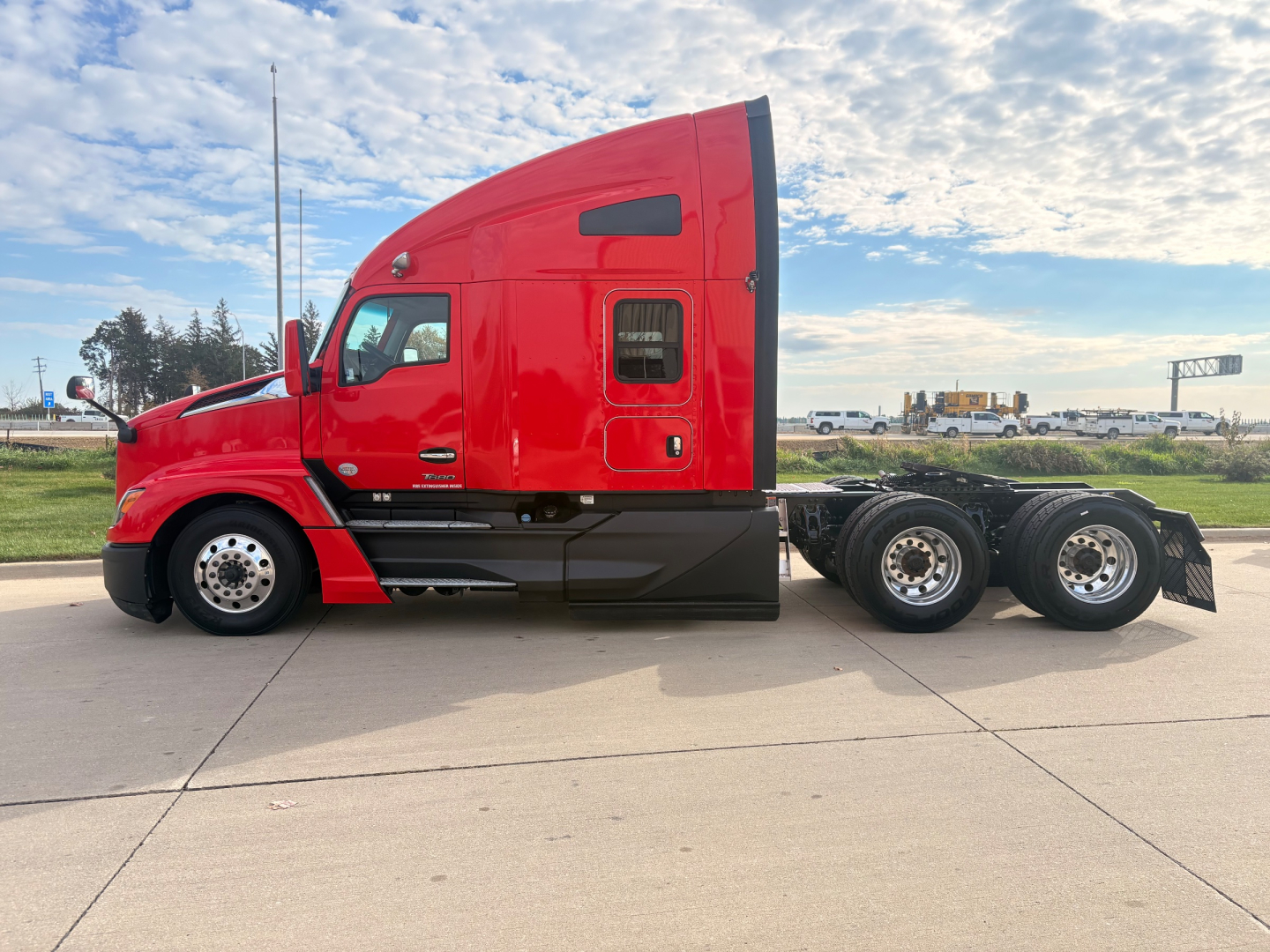 Kenworth T680 sleeper cab truck side profile showing red exterior, dual rear axles, and chrome fuel tanks with black undercarriage.