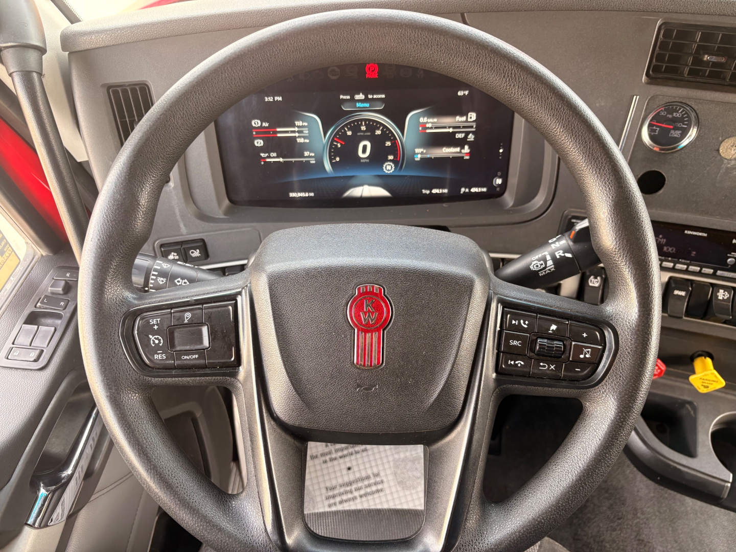 Kenworth T680 steering wheel and instrument cluster with digital dash showing speedometer and gauges.