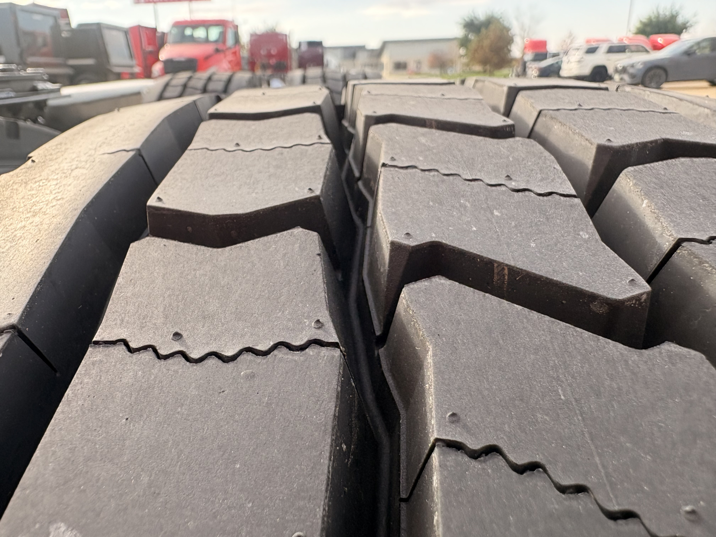 Tire tread close-up on Kenworth T680 truck chassis showing heavy-duty lug patterns and road grime.