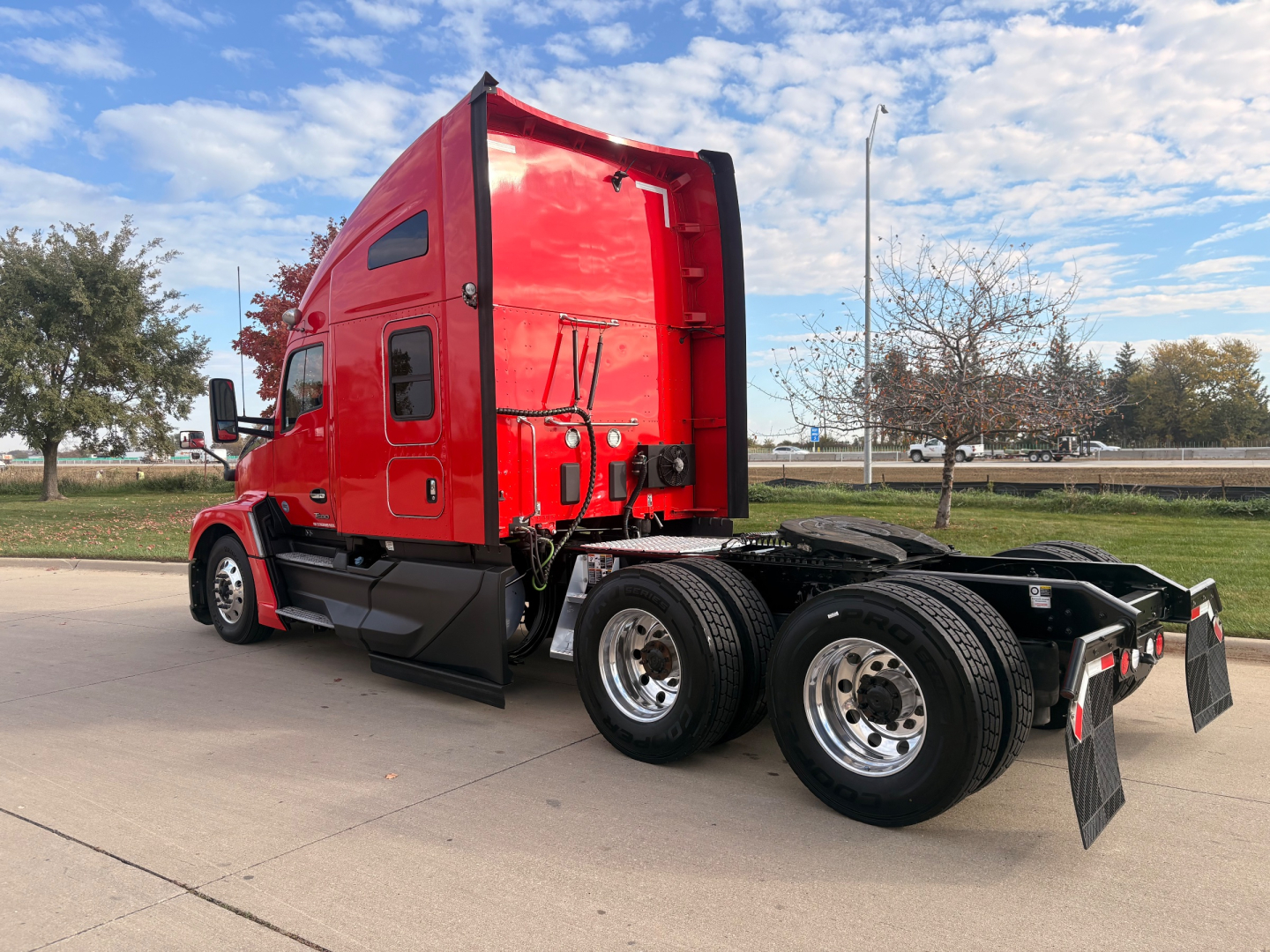 Kenworth T680 tractor cab in red, side view, showing tandem rear axles and fifth-wheel mount.