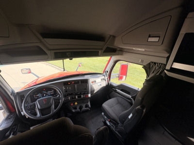 Kenworth T680 truck cab interior showing steering wheel dashboard and driver seat, with overhead storage compartments and window views.