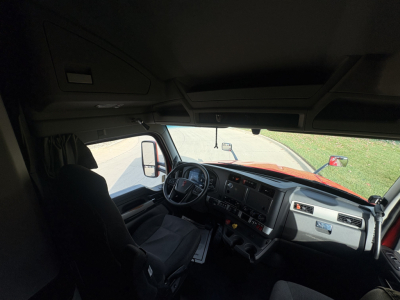 Kenworth truck cab interior with steering wheel, dashboard, and driver's seat visible.