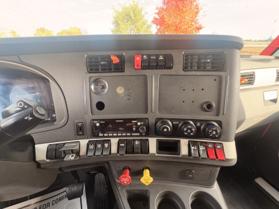Kenworth T680 dashboard cockpit showing driver controls, switches, knobs, and yellow and red control levers.