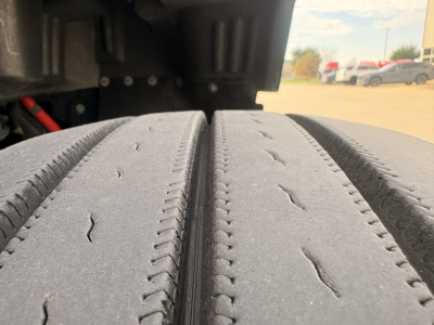Truck axle dual tires with tread detail and undercarriage visible in background.