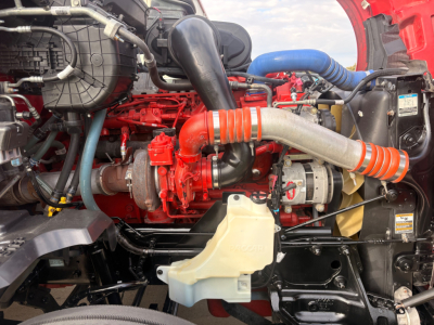 Kenworth T680 engine bay showing red turbocharger and intercooler piping, beige coolant reservoir, blue hose, and various labeled components.
