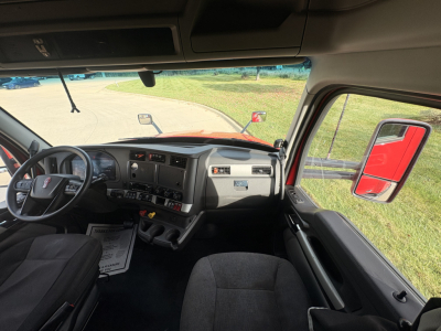 Kenworth T680 truck interior cab view showing steering wheel dashboard and driver's seat with large side mirror visible