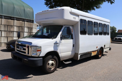 Ford E-350 shuttle bus with wheelchair lift, side windows, and a raised roof; number 113 on the top front; white paint with some rust at the lower panel.