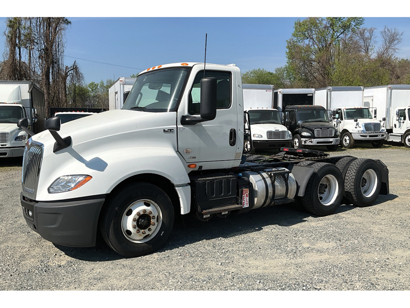 Truck chassis with Cab of a white 2020 International LT625 conventional daycab in a used-truck lot. Side view shows front wheel, fuel tanks, and dual rear axles.