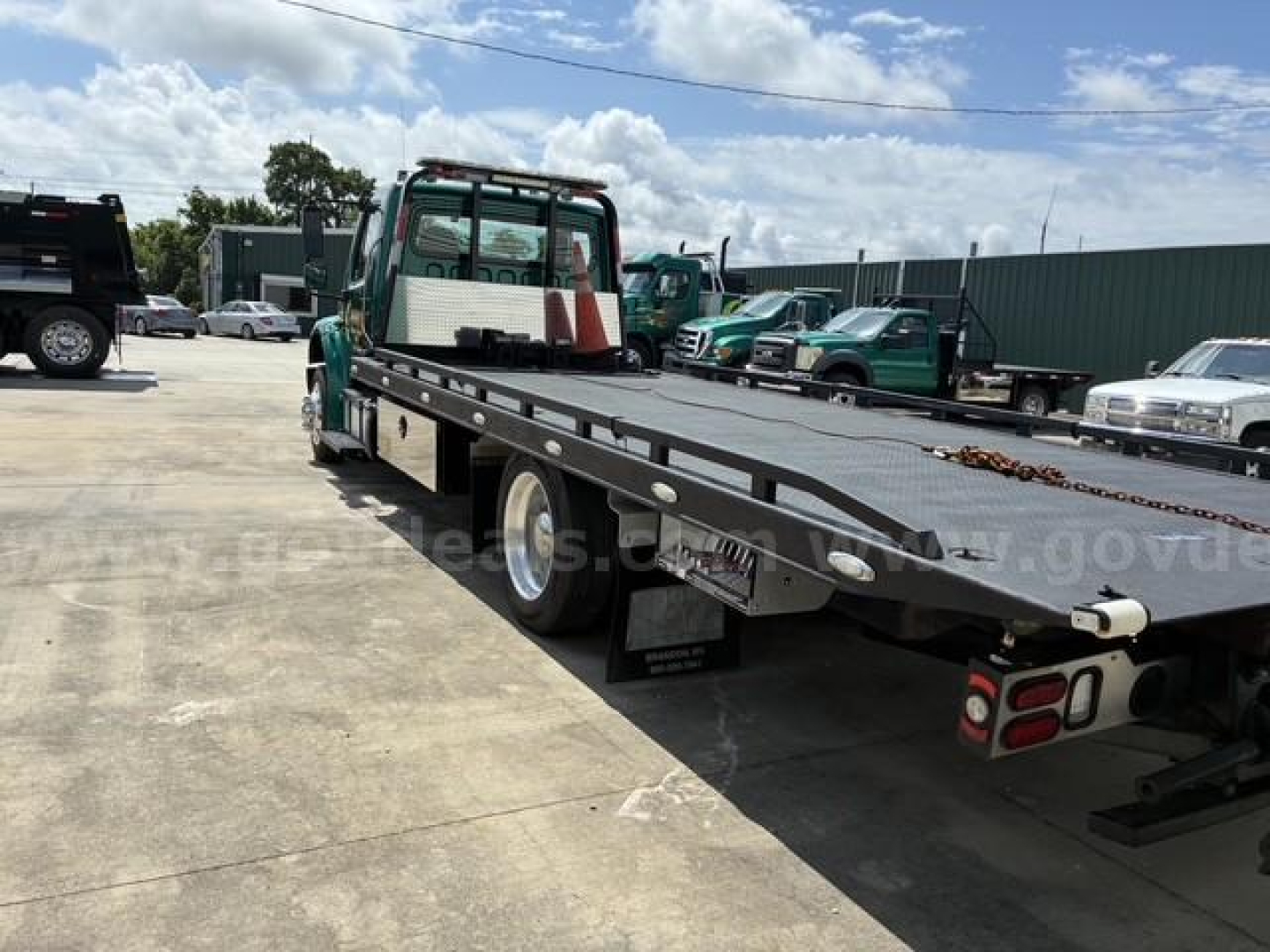 Freightliner M2 106 tow truck flatbed showing side view and rear deck with chains and lighting.