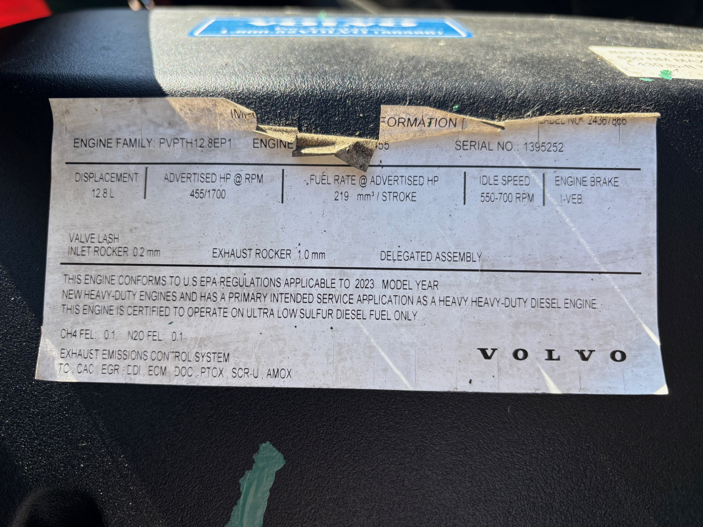 Volvo engine information label showing engine family, serial number, fuel rate, idle speed, and other specs on a dashboard placard.