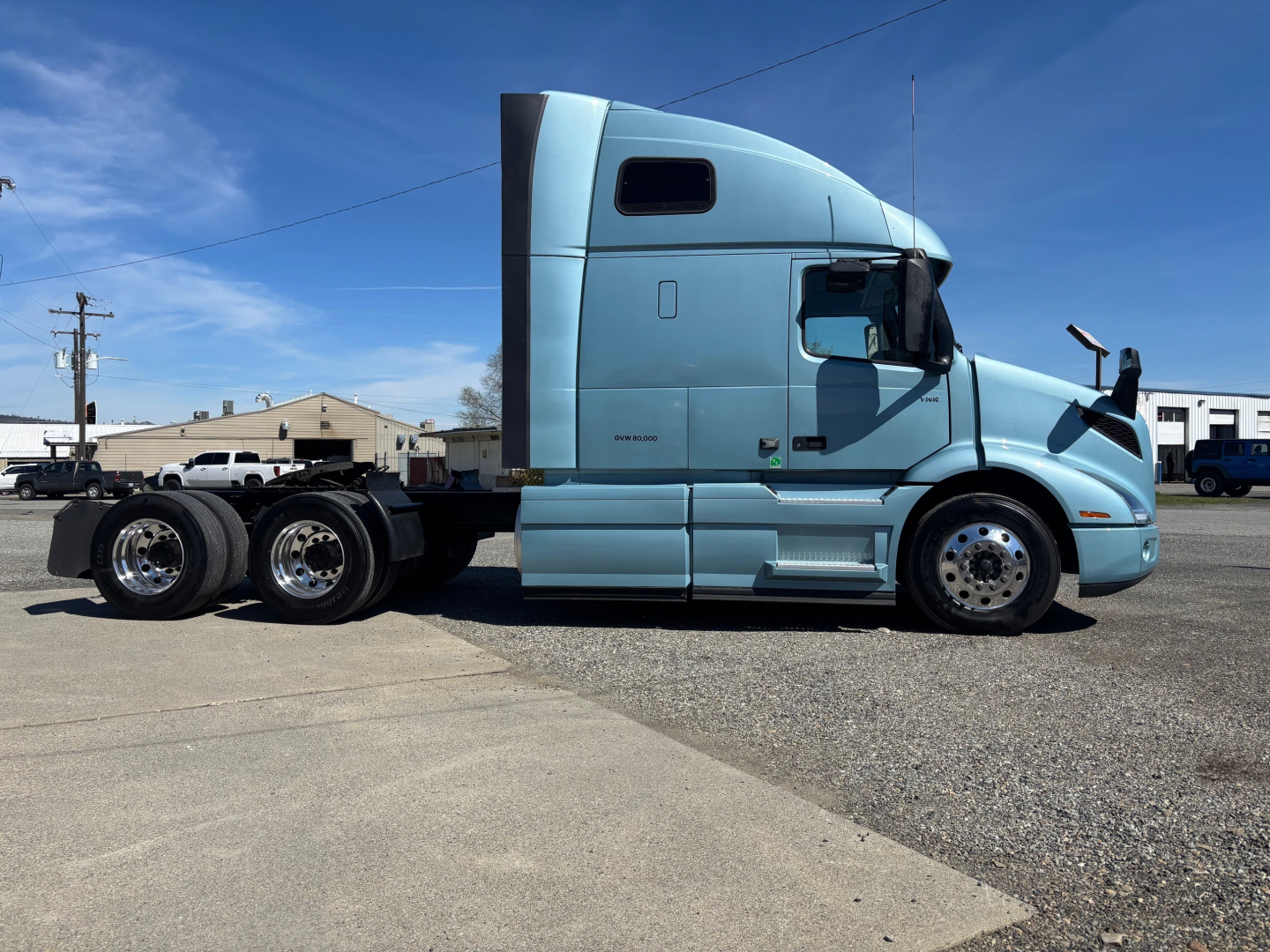 Volvo VNR64T660 truck side view showing sleeper cab and triple rear axles in blue.