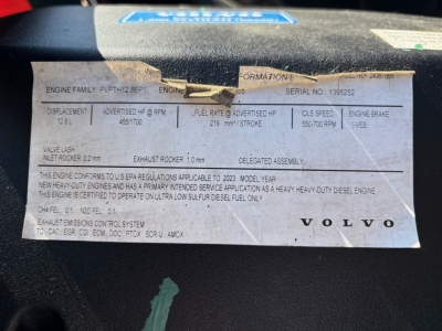 Volvo engine information label showing engine family, serial number, fuel rate, idle speed, and other specs on a dashboard placard.