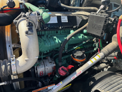 Volvo VNR64T660 engine bay showing green engine block, turbocharger piping, green hydraulic reservoir, and various hoses and wires.