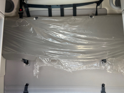Volvo VNR64T660 sleeper cab interior cargo area with plastic-covered mattress and tied strap.
