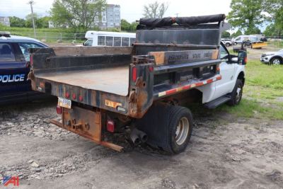 Ford F-350 Super Duty dump body truck rear view showing rusty flatbed and tailgate with rear lighting and dual rear axles.