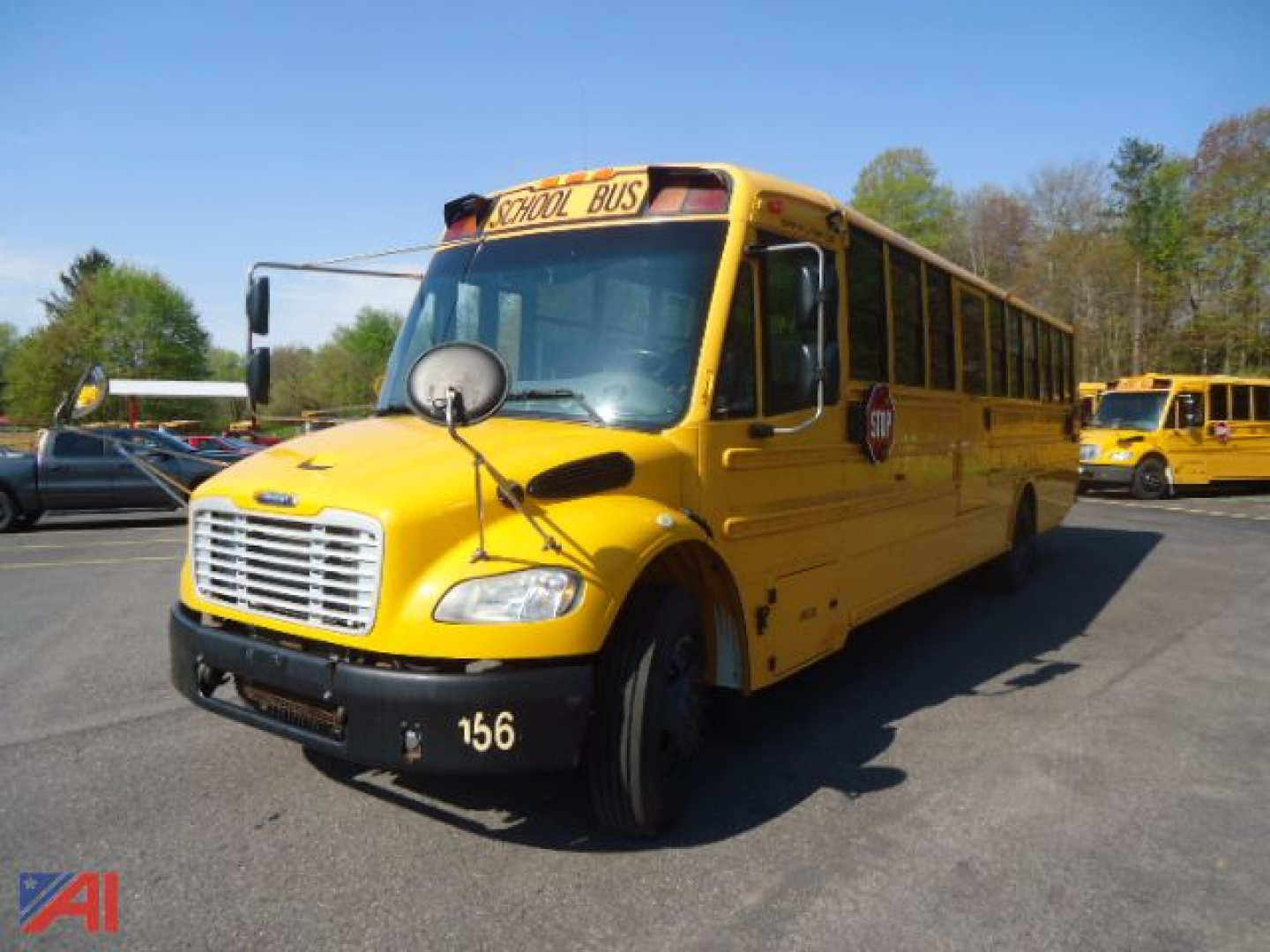 School bus front-left view showing yellow Freightliner Thomas B2 with 'SCHOOL BUS' sign on top, round warning light, black bumper, and bus number 156.