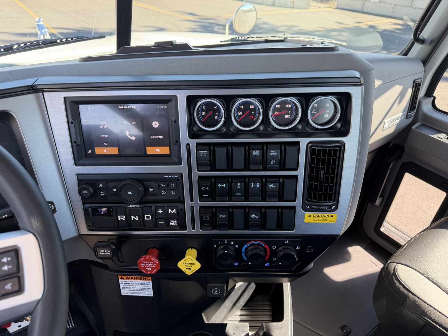 Dashboard of a 2027 Mack PI84T truck showing multiple gauges, infotainment screen, climate controls, and various switches.