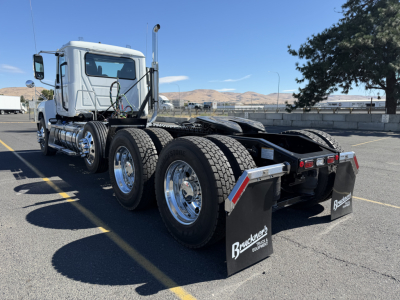Mack PI84T conventional daycab tractor rear view showing dual rear axles, chrome wheels, and black mud flaps with Bruckner's logo.