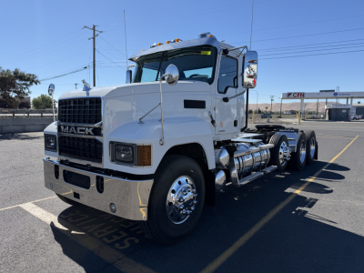 Mack PI84T conventional daycab truck in white, cab with large grille, dual rear axles, front bumper chrome, fuel tanks along side, parked in lot.