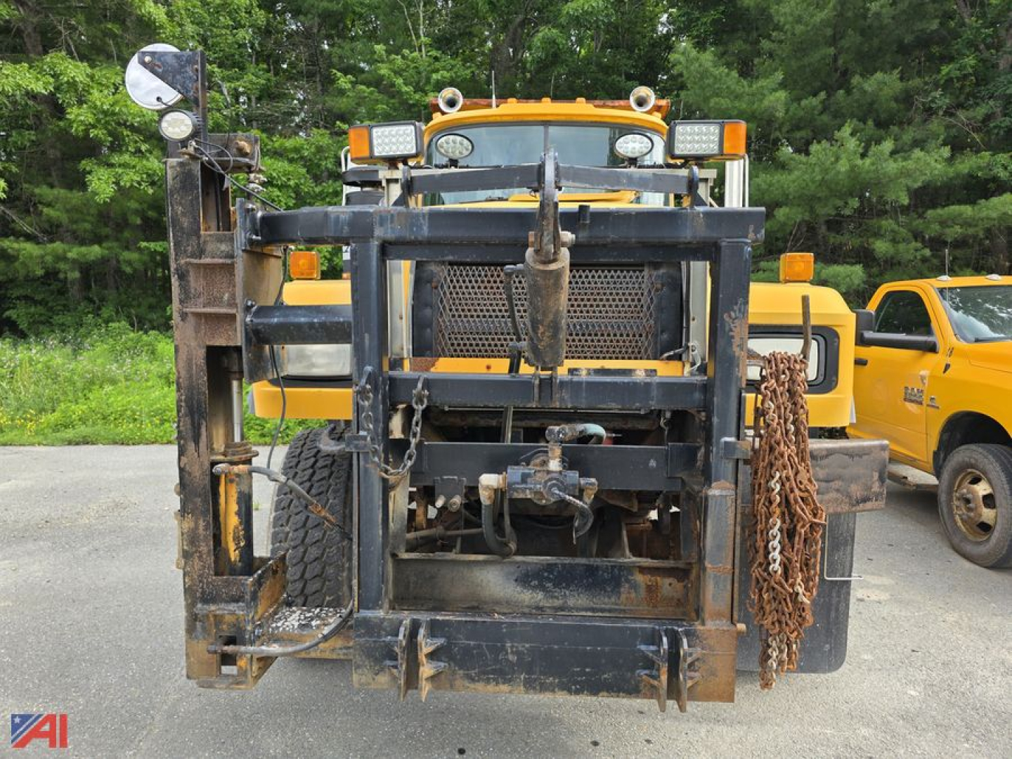 Front view of a yellow 2001 Mack RD690P dump truck with a sander body, showing the heavy-duty front frame, winch, and attached chains.