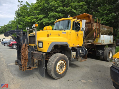 Mack RD690P dump truck with sander body in yellow, front view showing heavy-duty tires and snow plow attachment; large hopper at rear.