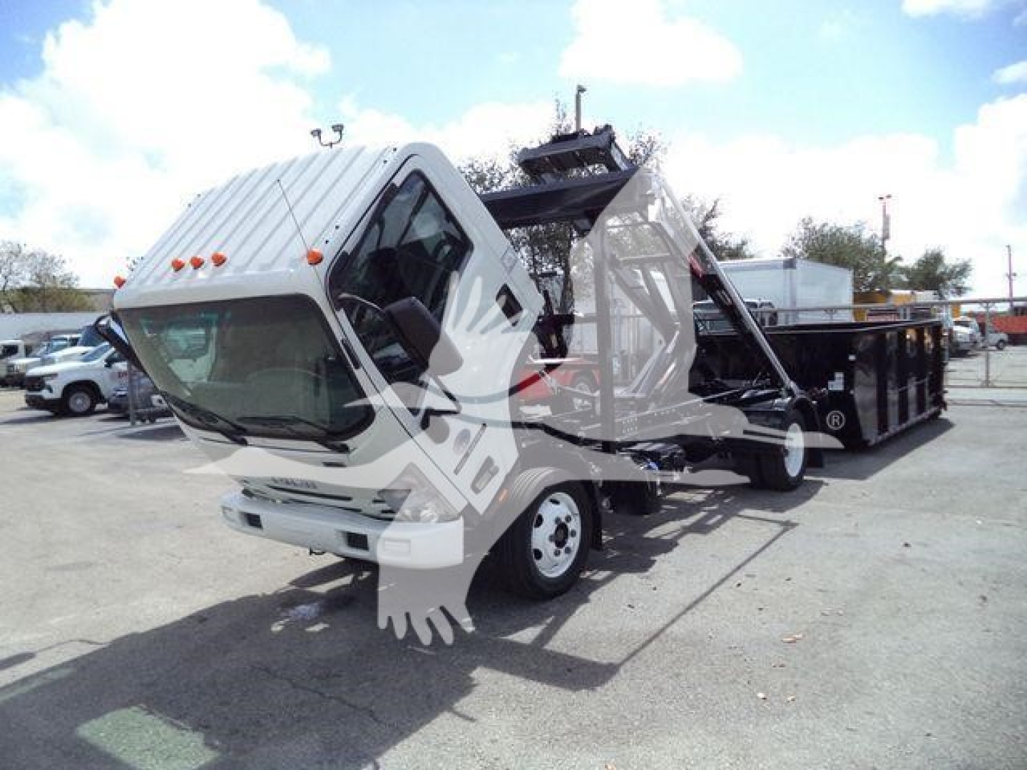 Isuzu NPRR truck cab tilted with roll-off container on a lot