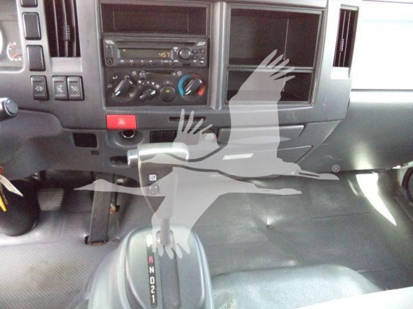 Isuzu NPR/Nrr truck interior dashboard and gear shifter area showing climate controls and radio with a watermark overlay.