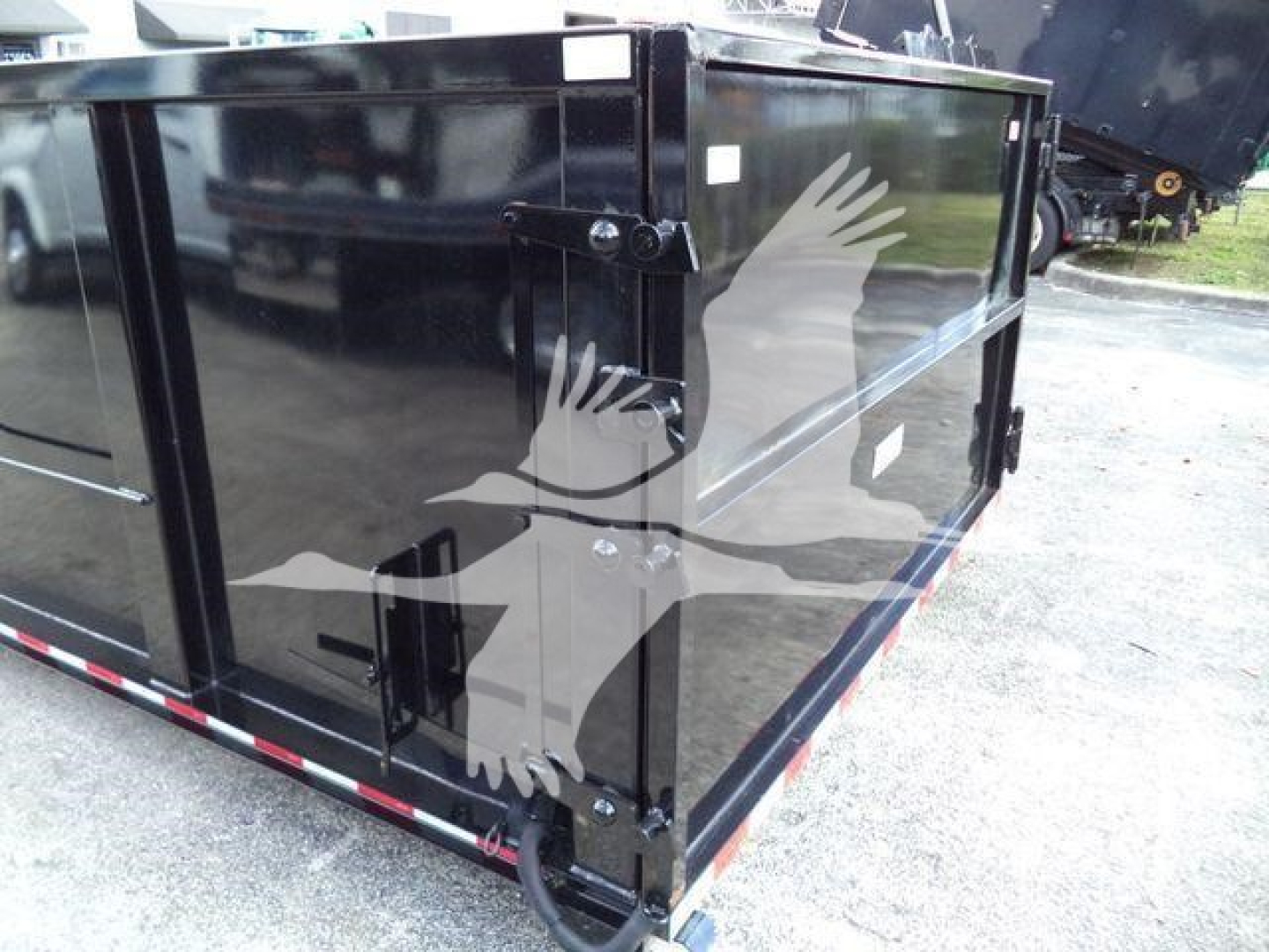 Isuzu NPRR roll-off truck dump body side view showing black metal cargo container with latch hinges and reflective logo