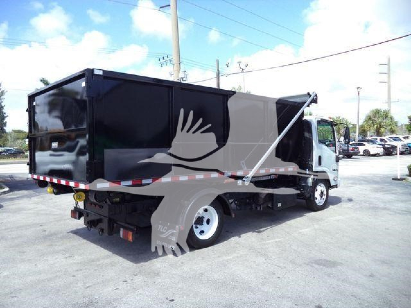 Isuzu NPR/NRR dump truck in service showing cargo bed and cab with black container and white wheel.