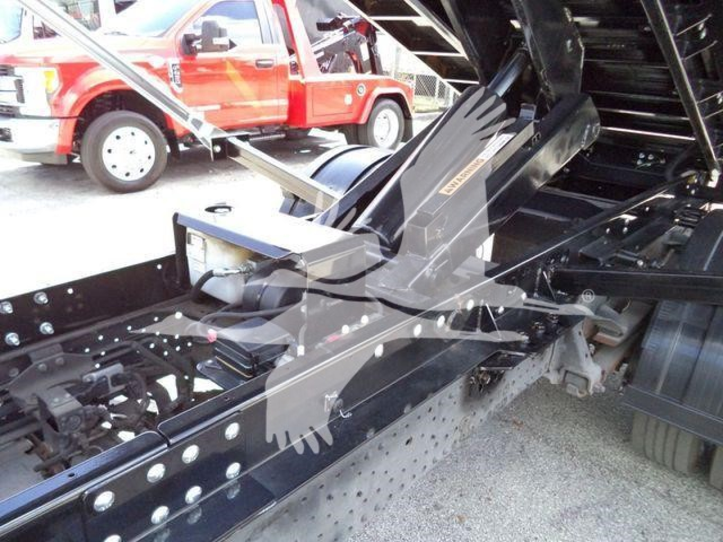 Isuzu NPRR truck chassis showing fifth-wheel/boom linkage and hydraulic components in the bed area.