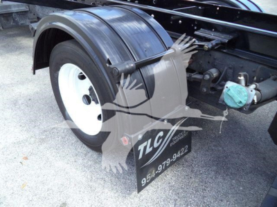 Isuzu NRR wheel, fender, and mudflap view showing rear wheel well and green fluid cap