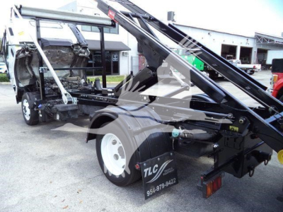 Isuzu NPR/RR truck chassis with roll-off hoist and wheel, side view showing hydraulic arms and TLC sticker on rear wheel area.