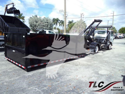 Isuzu NPRR roll-off truck with large black outer container and loading hoist in yard; visible TLC Truck & Equipment logo watermark.