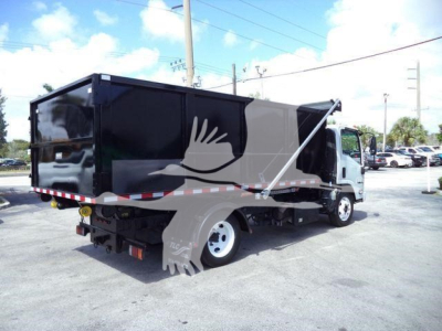 Isuzu NPR/NRR dump truck in service showing cargo bed and cab with black container and white wheel.