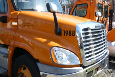 Freightliner Cascadia hood area showing orange truck with number 1988 and chrome grille.