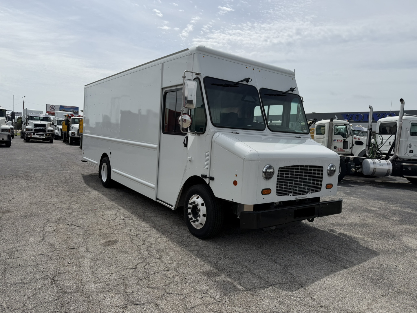 Boxy white 2025 Harbinger S554 step van, front-left view, cargo area with black grille, large cab windows, side mirror, and basic wheels.
