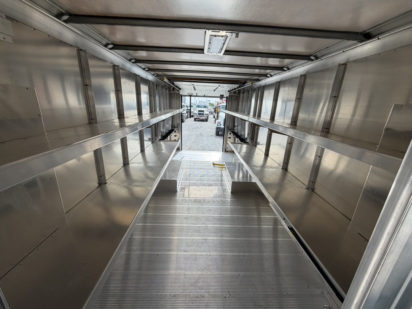 Harbinger S554 step van interior cargo area showing stainless steel walls and metal floor with loading ramp at far end.