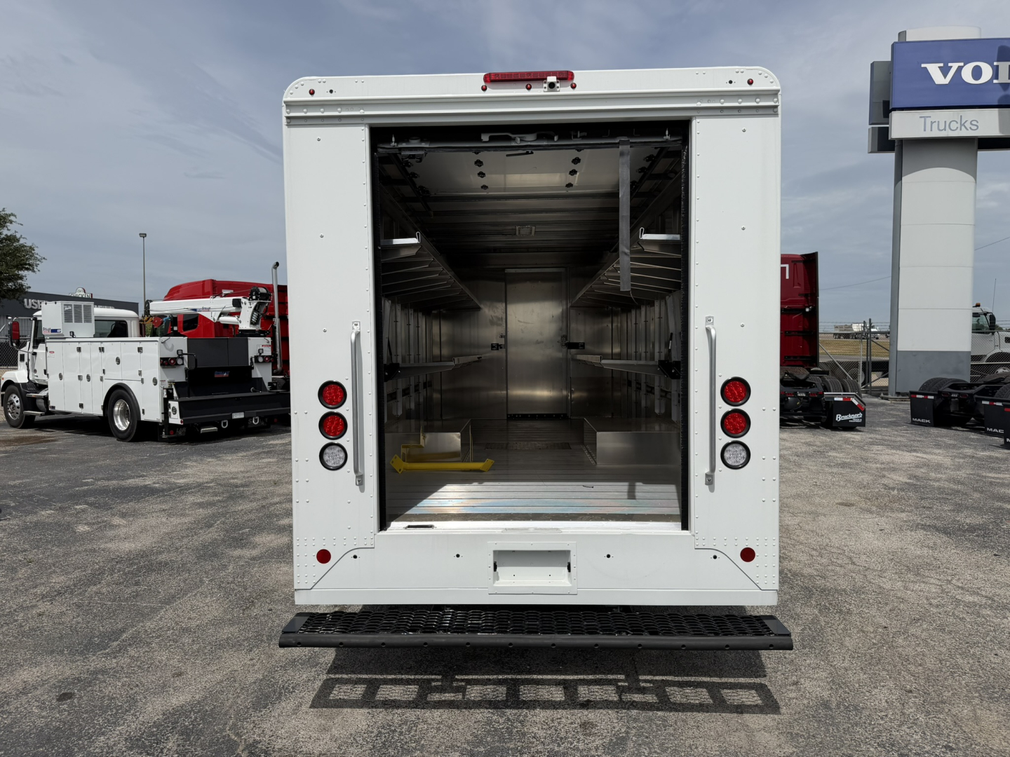 Truck cargo area open at rear showing empty aluminum interior with wall posts and bright lighting.