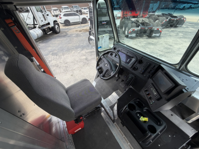 Truck cab interior showing steering wheel, dashboard, and center console of a Harbinger S554 step van, with driver seat and control panels.