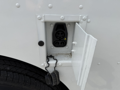 Harbinger S554 step van side inlet showing electrical power inlet with two round sockets and protective door, mounted on white body panel.