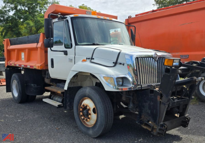 2003 International WorkStar 7300 dump truck with plow, white cab orange dump bed, front plow mount visible, large chrome grille.