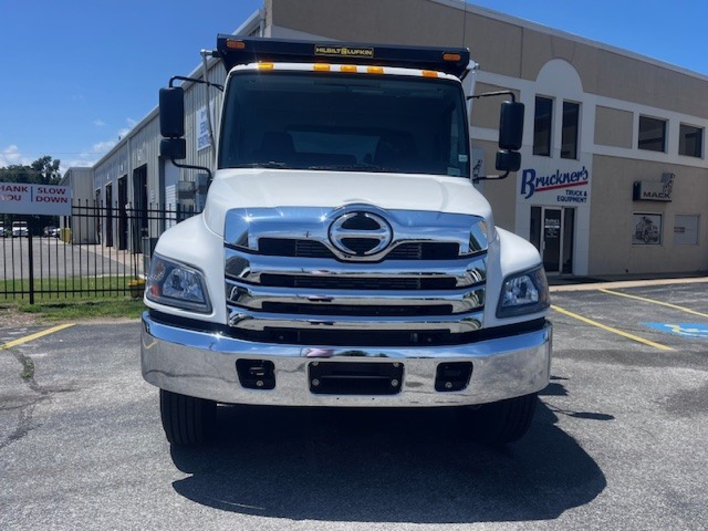 Front view of a 2026 Hino L7 dump truck showing chrome grille and bumper, Hino emblem, and large headlights.