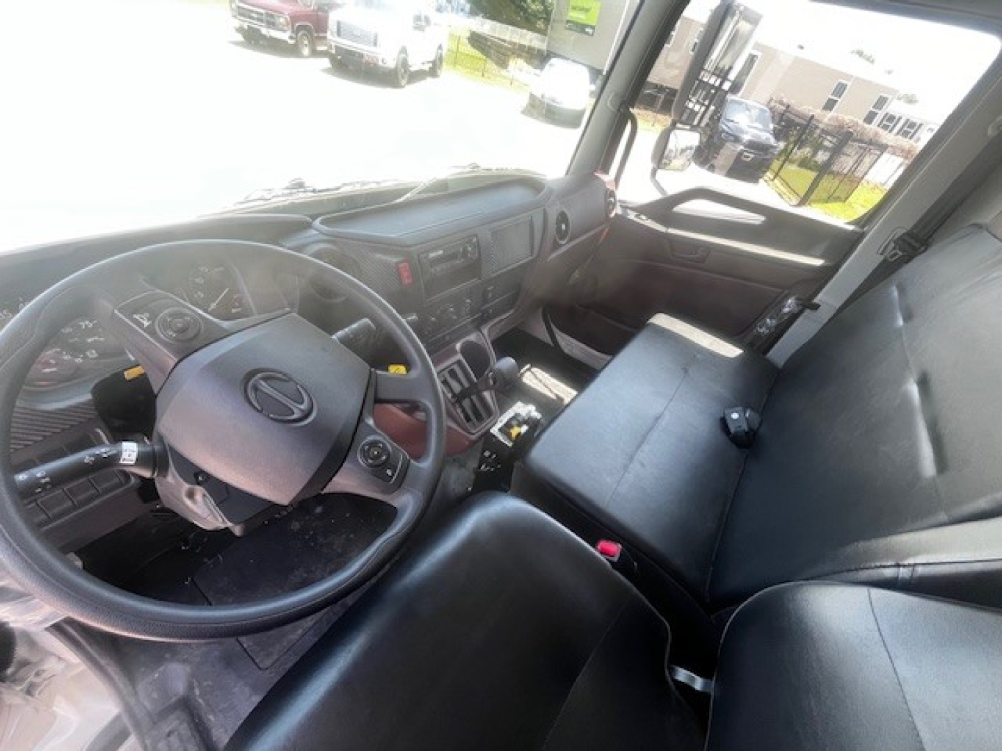 Interior cabin of 2026 Hino L7 dump truck showing steering wheel and front bench seat.