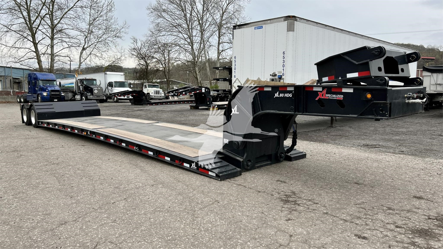 Trailer showing XL Specialized Mini Deck lowboy with extended flatbed and hydraulic gooseneck, black with decals, in a used trailers lot.