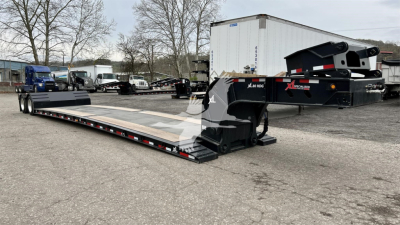 Trailer showing XL Specialized Mini Deck lowboy with extended flatbed and hydraulic gooseneck, black with decals, in a used trailers lot.