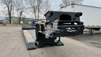 Lowboy trailer connection area with ramps and hydraulic components; visible text on labels includes VIN and stock details in listing with heavy equipment.