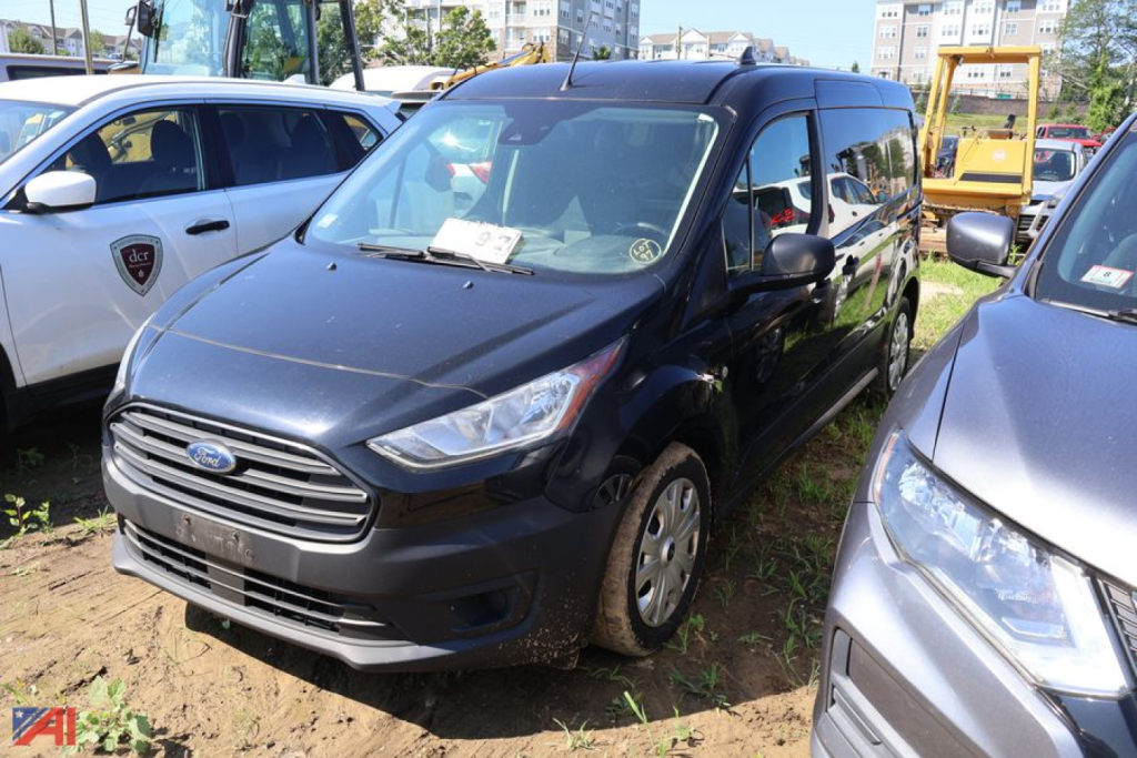 2019 Ford Transit Connect Cargo Van parked in a lot with other vehicles; front grille with Ford emblem visible.