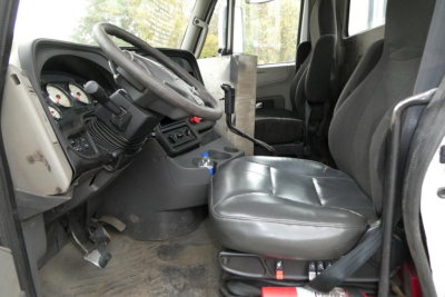 Truck cab interior showing steering wheel, dashboard gauges, and driver's seat of a 2013 International PROSTAR+ 113 daycab.