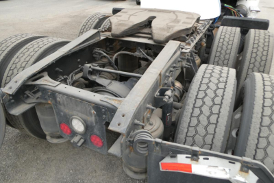 Tractor-trailer chassis showing rear frame and fifth wheel area with dual rear axles and tires; includes components like air tanks, hoses, and electrical wiring.